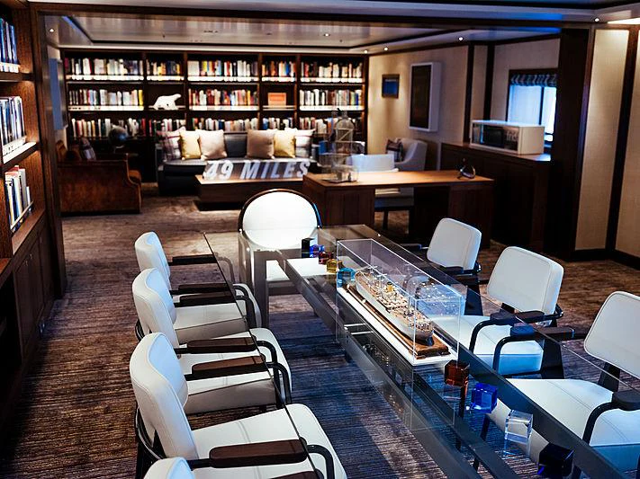 a room with a table chairs and a bookcase aboard PLANET NINE Yacht for Charter