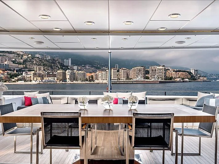 a table with chairs and a view of a city aboard THANUJA Yacht for Sale