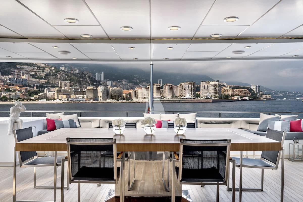 a table with chairs and a view of a city aboard THANUJA Yacht for Sale