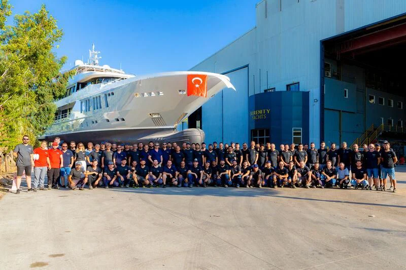 a group of people posing for a photo in front of a large ship aboard THANUJA Yacht for Sale