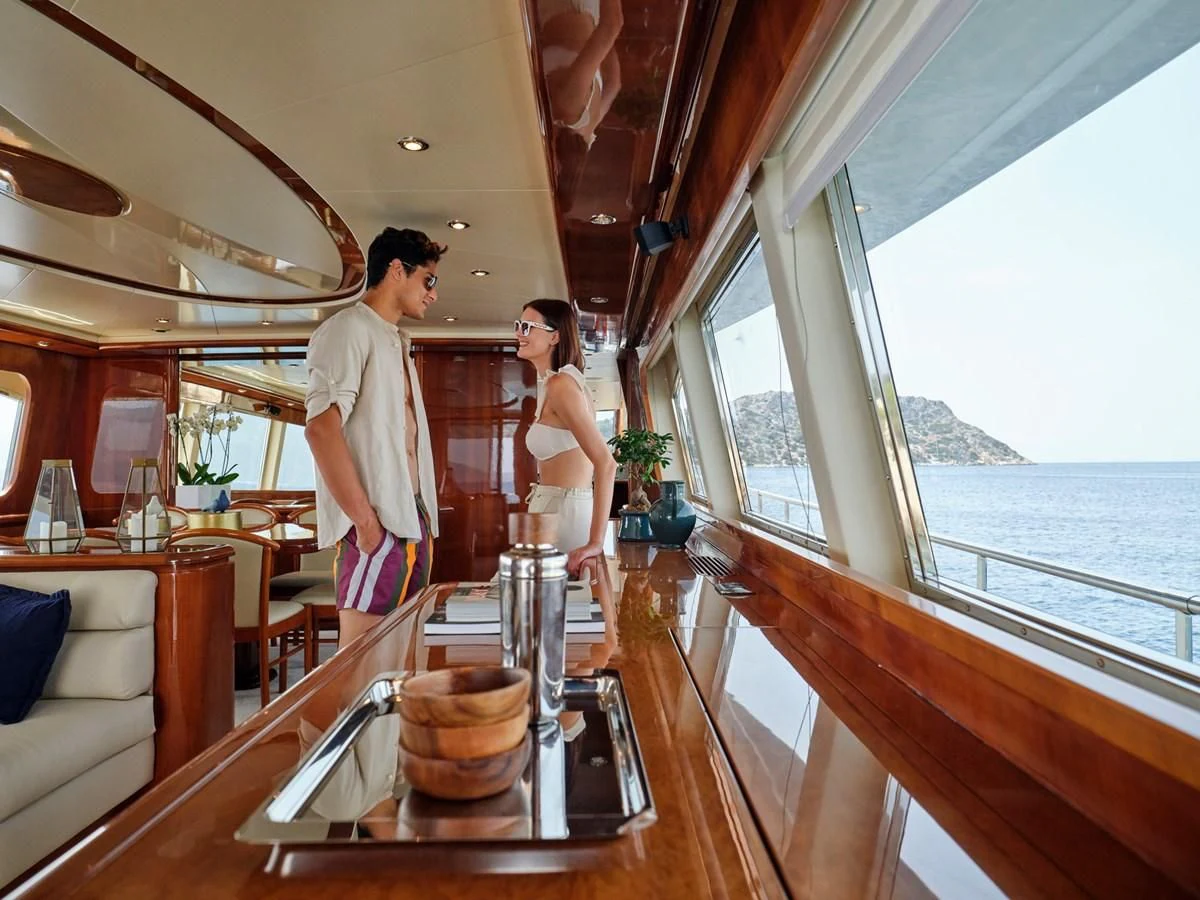 a man and a woman standing in a room with a table and chairs aboard ESTIA POSEIDON Yacht for Charter