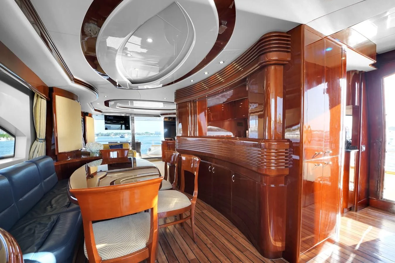 a room with a wood cabinet and chairs and a table with a couch aboard AZIMUT 80 2003 Yacht for Sale