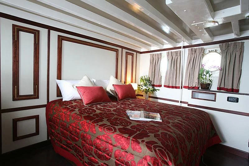 a bed with red pillows aboard CALISTO Yacht for Sale