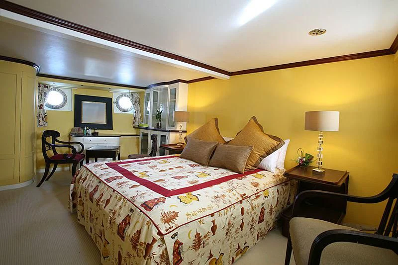 a bedroom with a bed and a chair aboard CALISTO Yacht for Sale