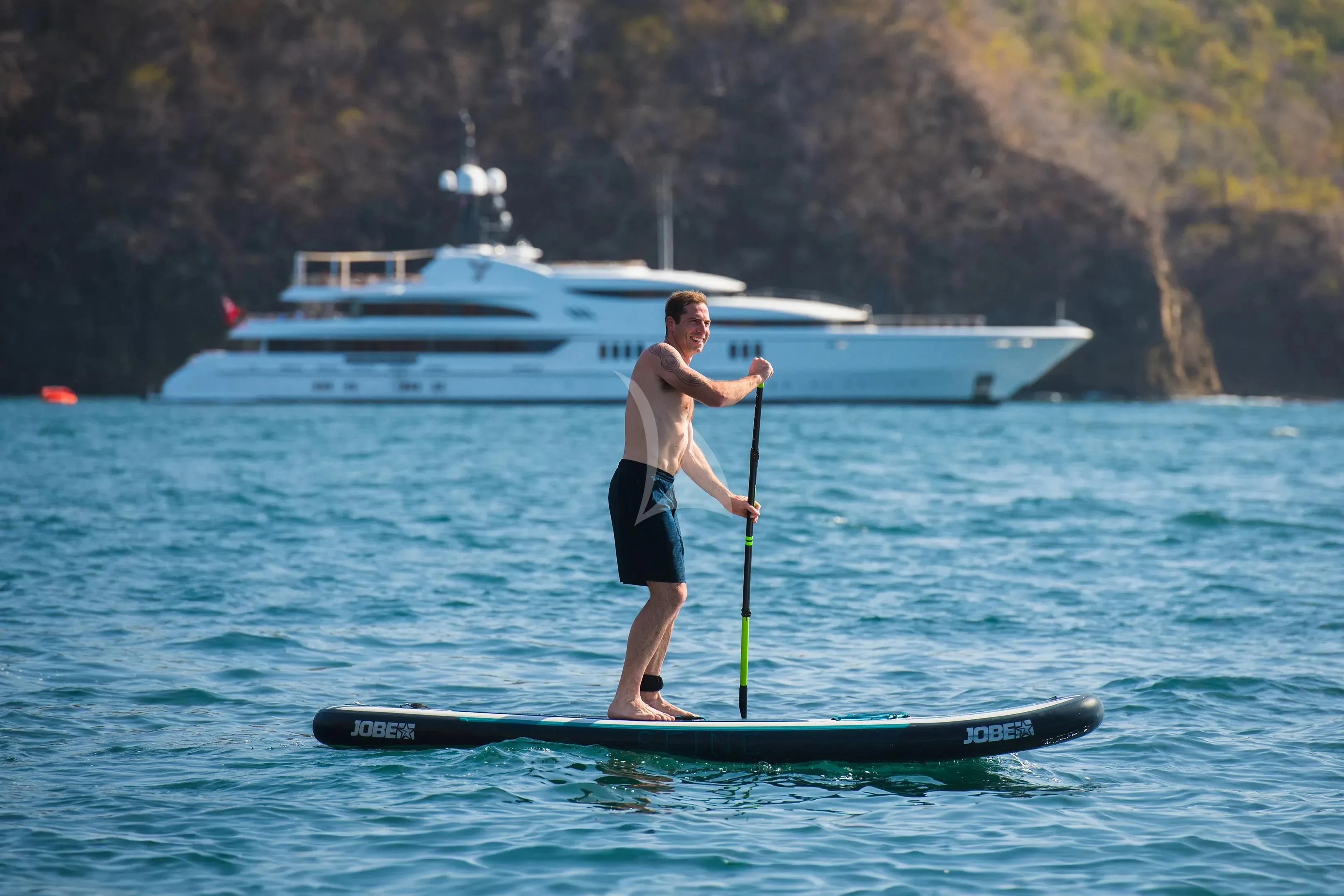 a man paddle boarding aboard FIREBIRD Yacht for Charter
