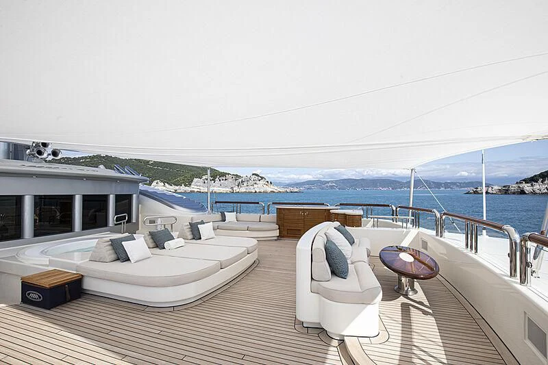 a deck with a view of the ocean and a large boat aboard FIREBIRD Yacht for Charter
