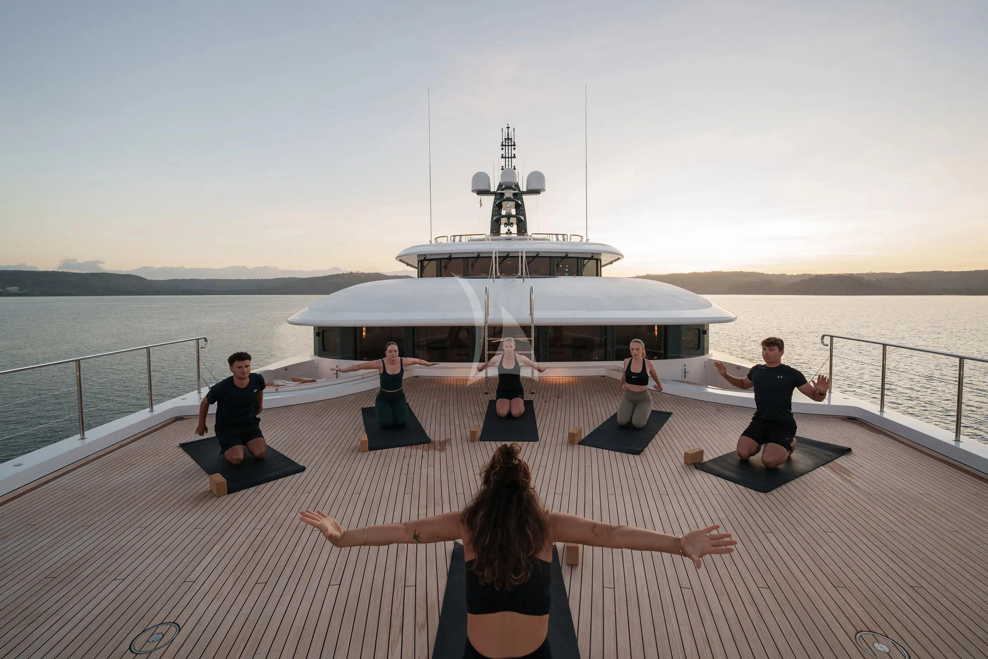 a group of people doing yoga on a deck by a large ship aboard FIREBIRD Yacht for Charter