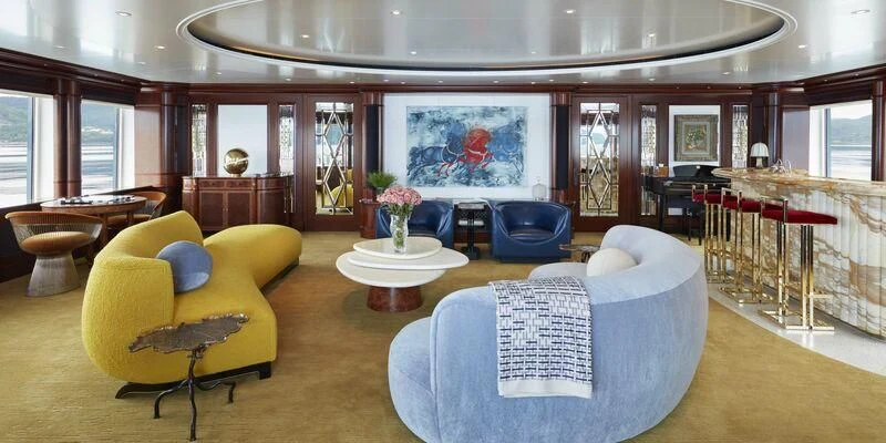 a large living room with a blue couch and a large painting aboard FIREBIRD Yacht for Charter