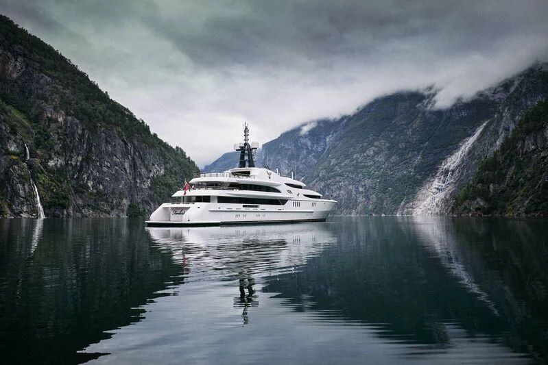a boat on the water with Geirangerfjord in the background aboard FIREBIRD Yacht for Charter