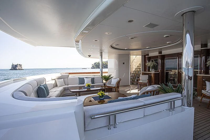 a large white lounge chair next to a large white bed and a large body of water aboard FIREBIRD Yacht for Charter