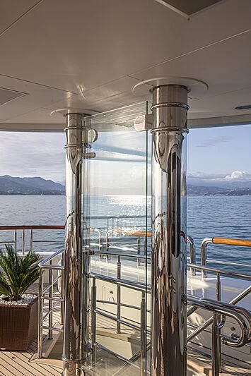 a deck with a railing and a body of water in the background aboard FIREBIRD Yacht for Charter