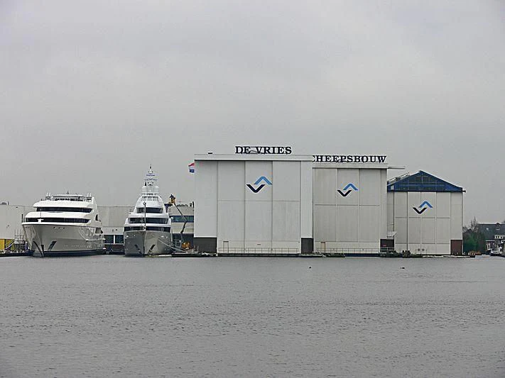 a large white building next to a boat and a smaller boat aboard FIREBIRD Yacht for Charter