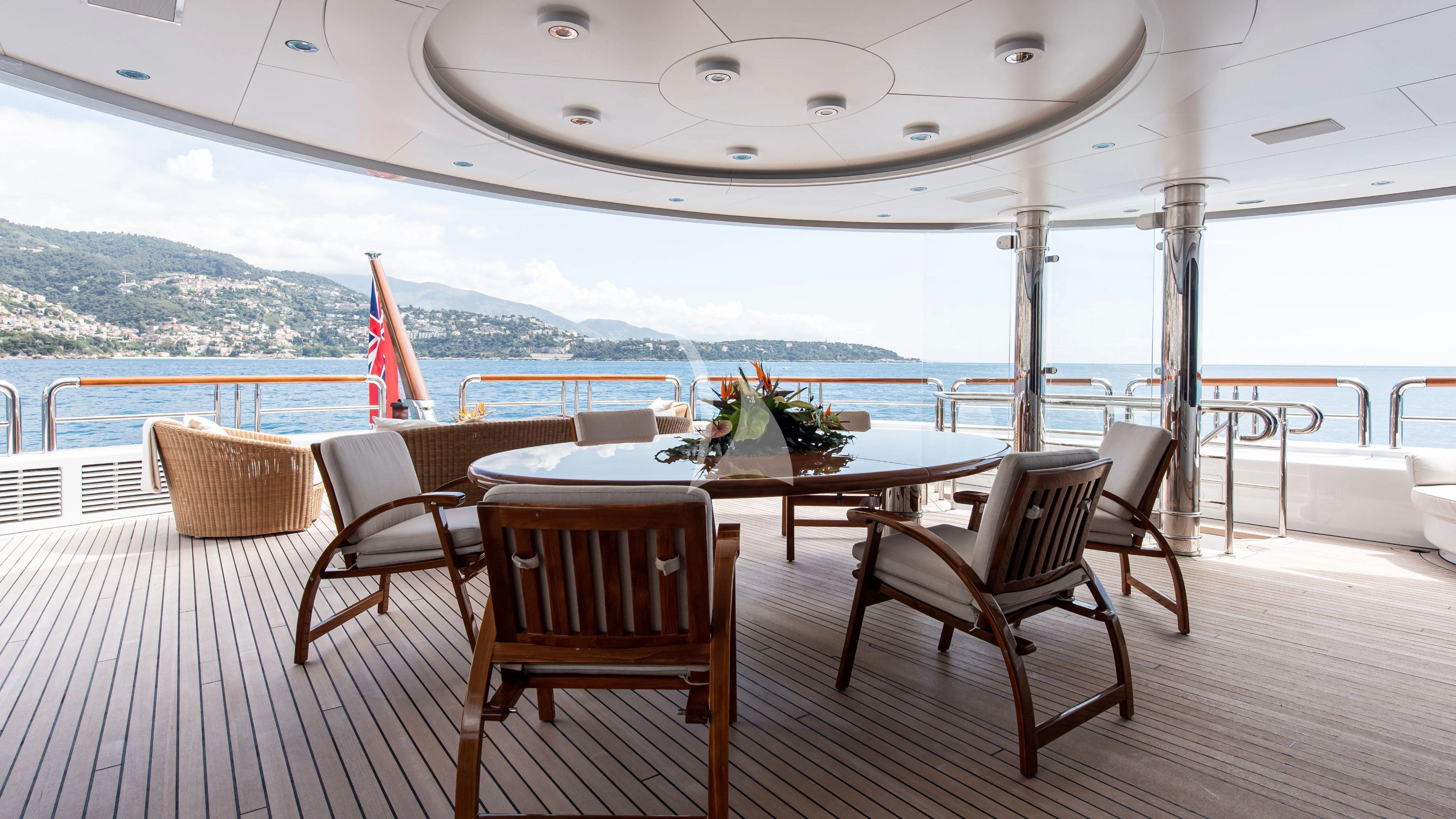 a table and chairs on a deck overlooking a large body of water aboard FIREBIRD Yacht for Charter