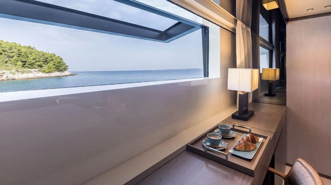 a table with food on it by a window with a view of the ocean aboard EROS Yacht for Sale