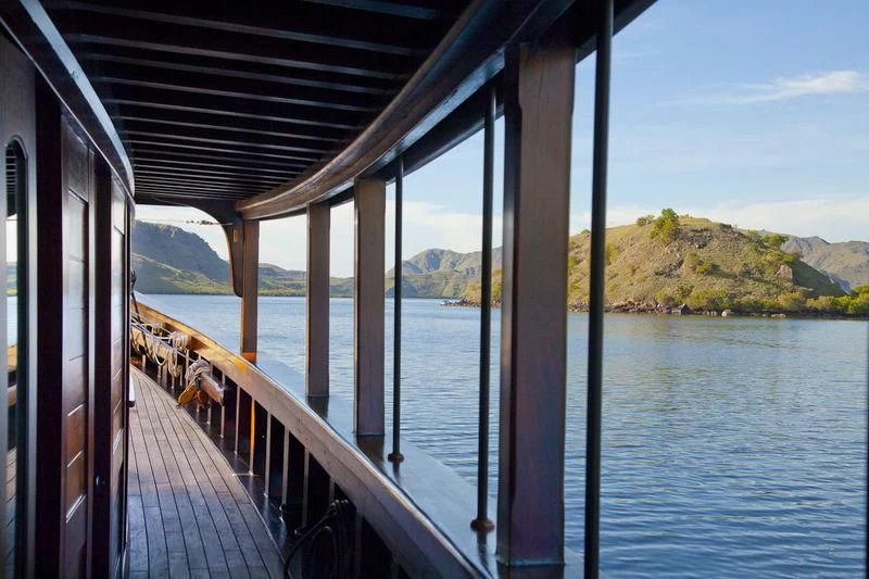 a deck with a view of the water and mountains in the background aboard DUNIA BARU Yacht for Charter
