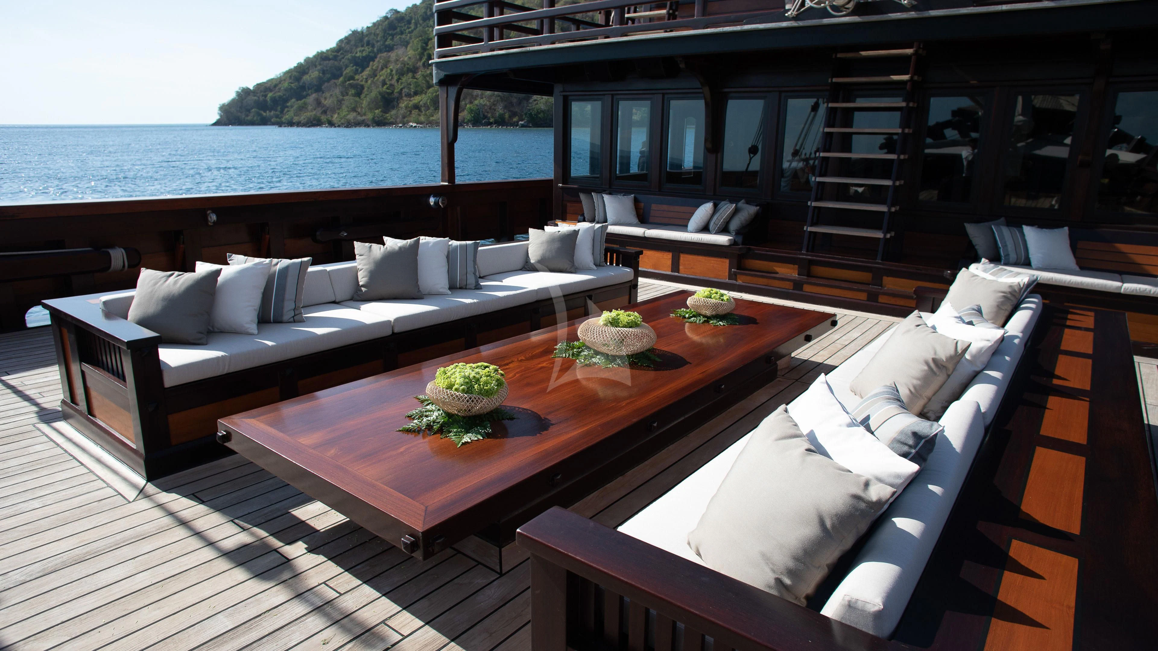 a living room with a large sofa and a table with a large window aboard DUNIA BARU Yacht for Charter