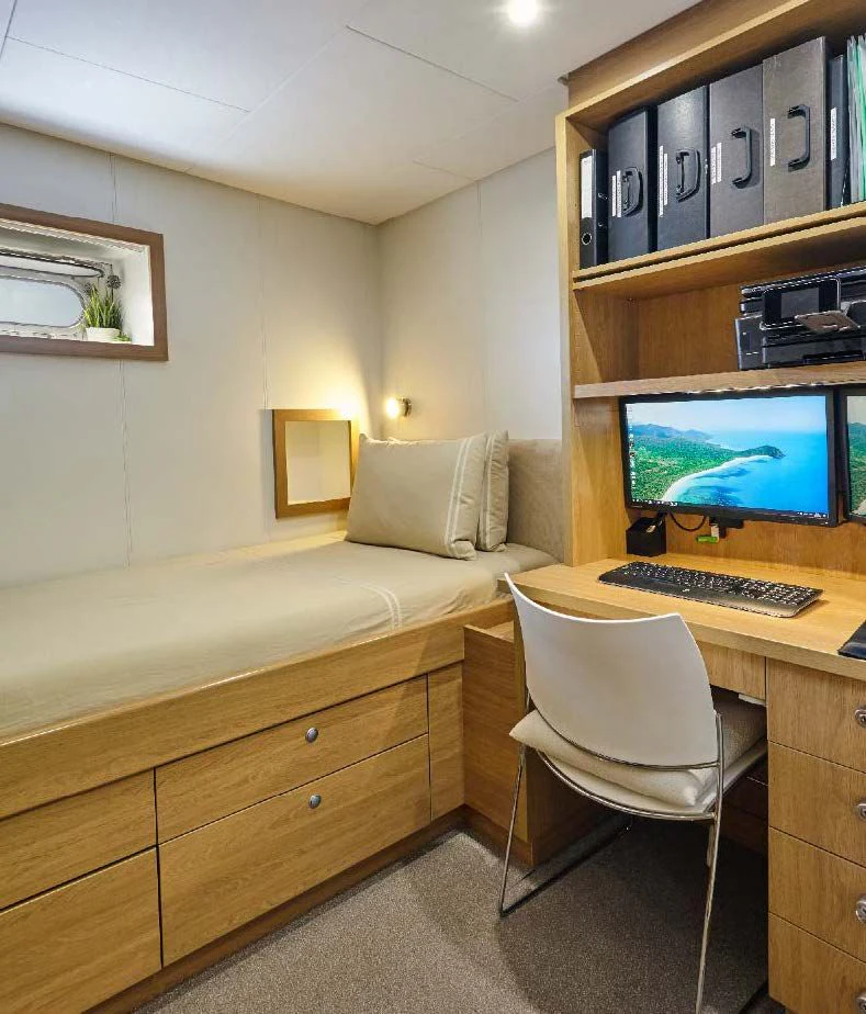 a room with a desk and a bed aboard KALM Yacht for Sale