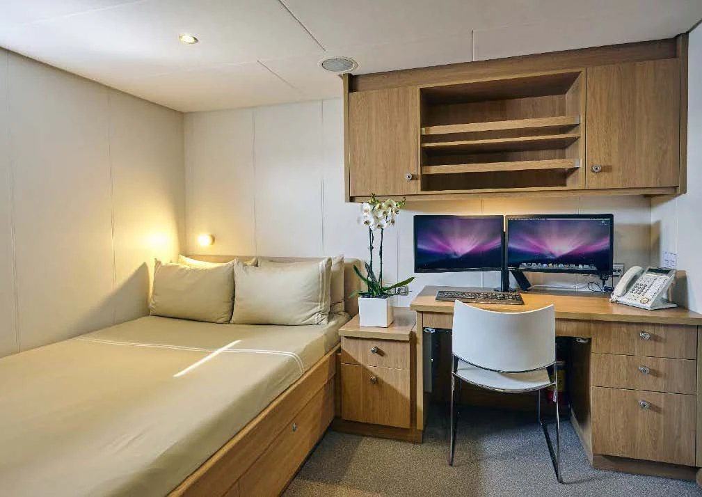 a bedroom with a bed and desk aboard KALM Yacht for Sale