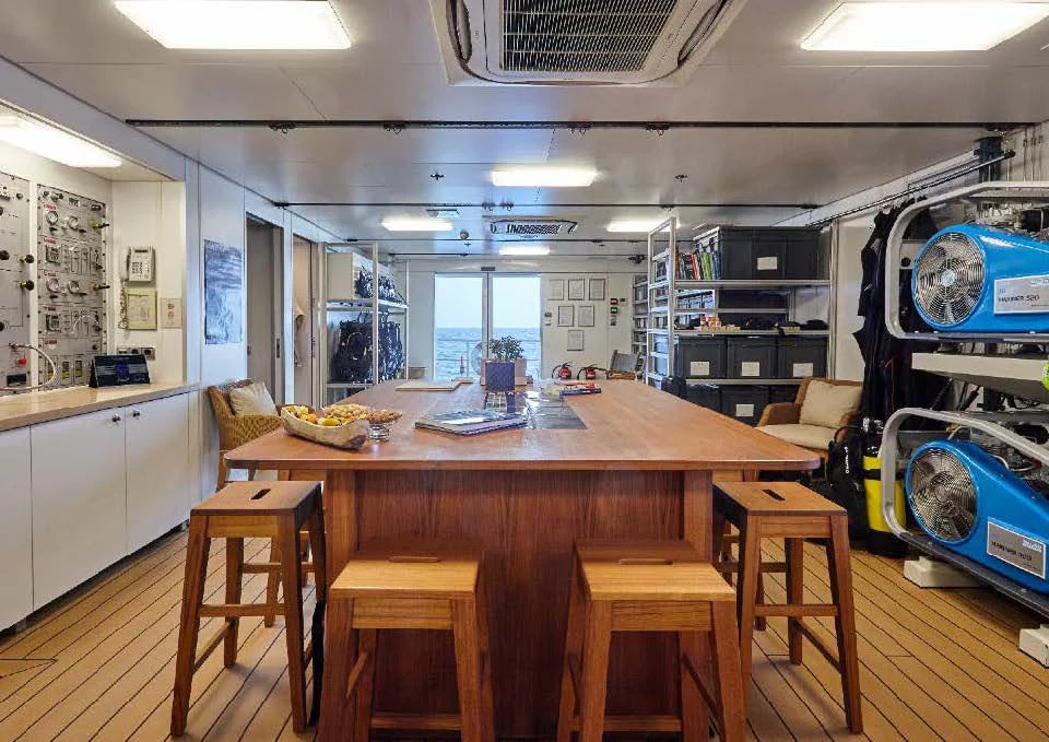 a room with tables and chairs aboard KALM Yacht for Sale
