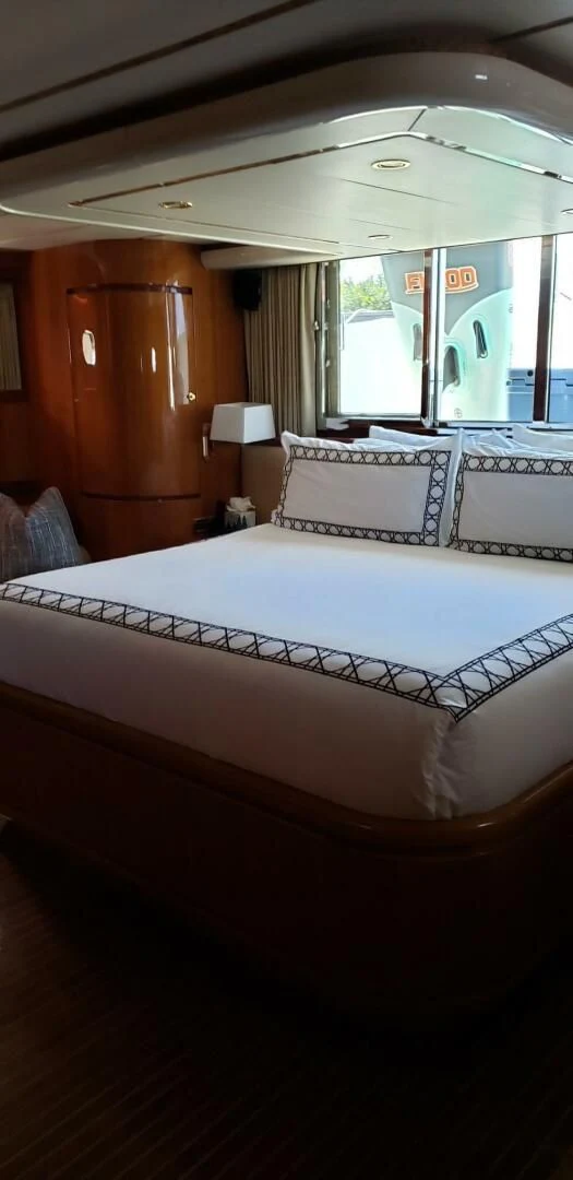 a bed with a white sheet and a wooden door aboard TORTUGA Yacht for Sale