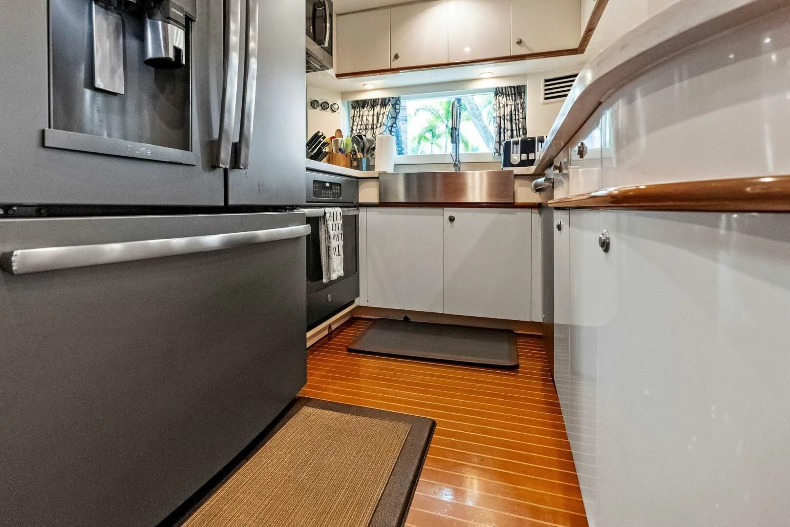a kitchen with a stainless steel microwave oven and a wood floor aboard TORTUGA Yacht for Sale