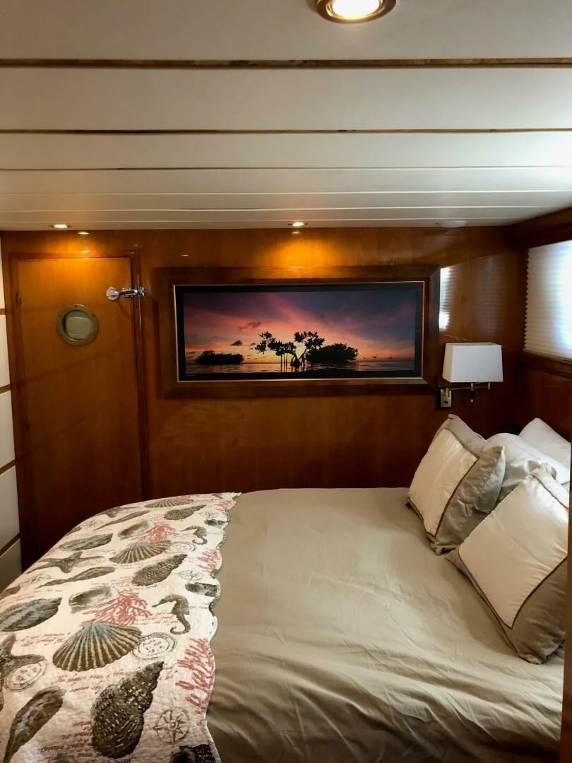 a bed with a painting on the wall aboard TORTUGA Yacht for Sale