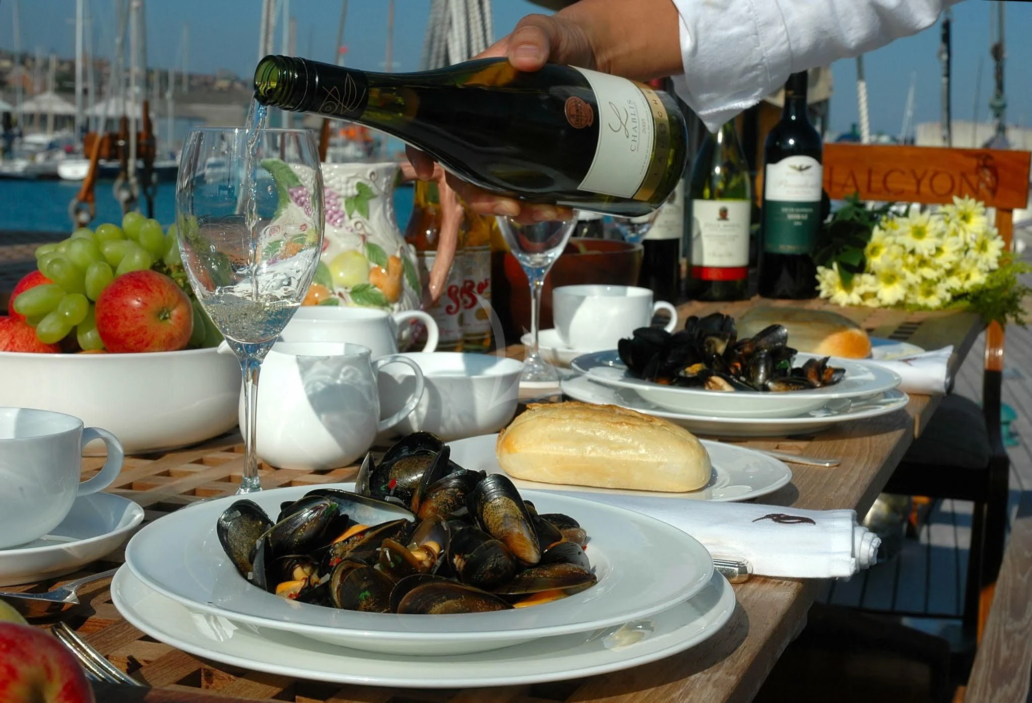 a person pouring wine into a glass aboard HALCYON Yacht for Sale