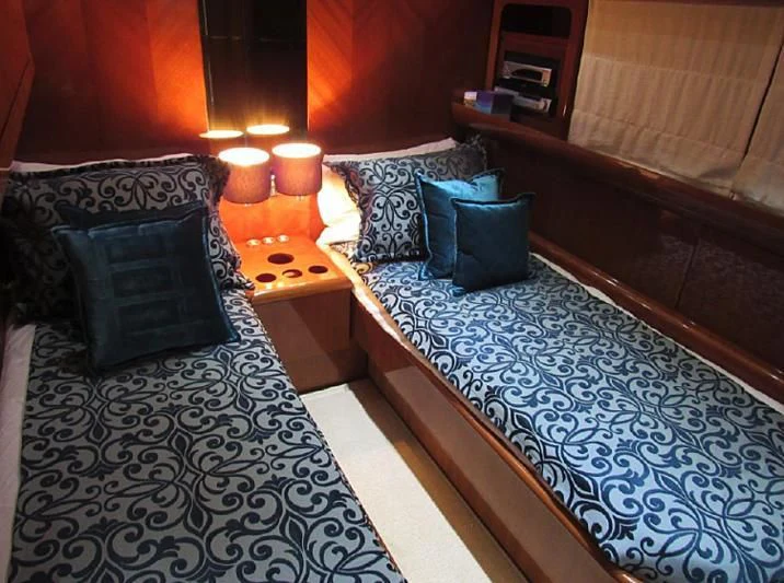a bed with a blue and white bed spread and pillows aboard ENDERA Yacht for Sale