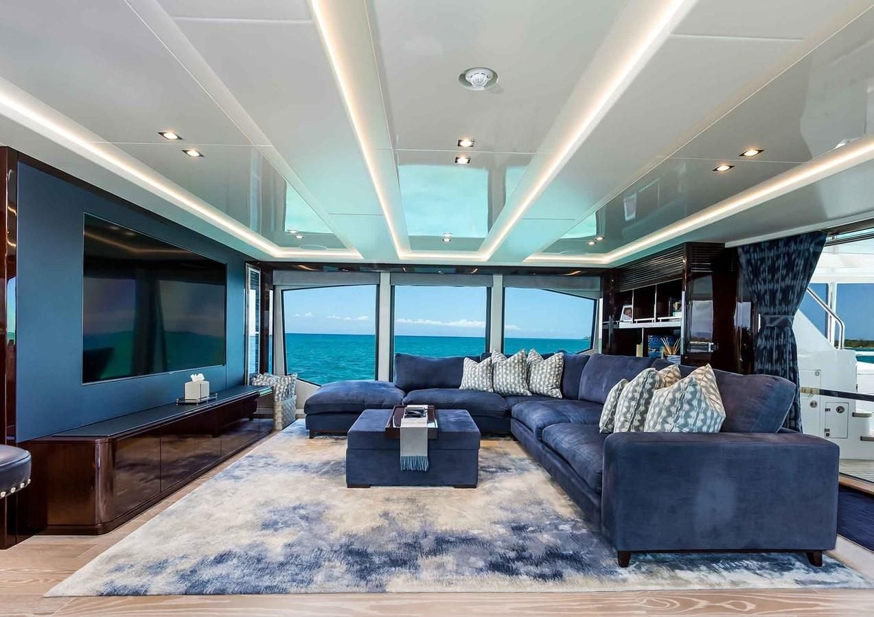 a living room with a large blue couch and a large flat screen television aboard CAPTAIN MORGAN III Yacht for Sale