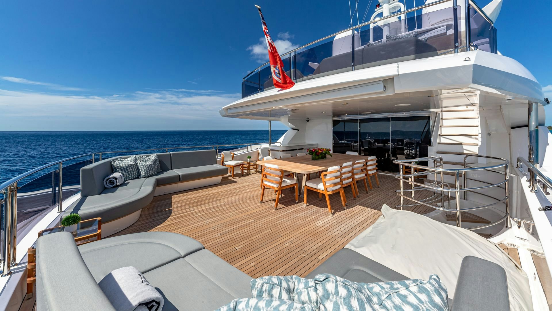 a deck with a large body of water and a deck with chairs and tables and a large boat aboard CAPTAIN MORGAN III Yacht for Sale