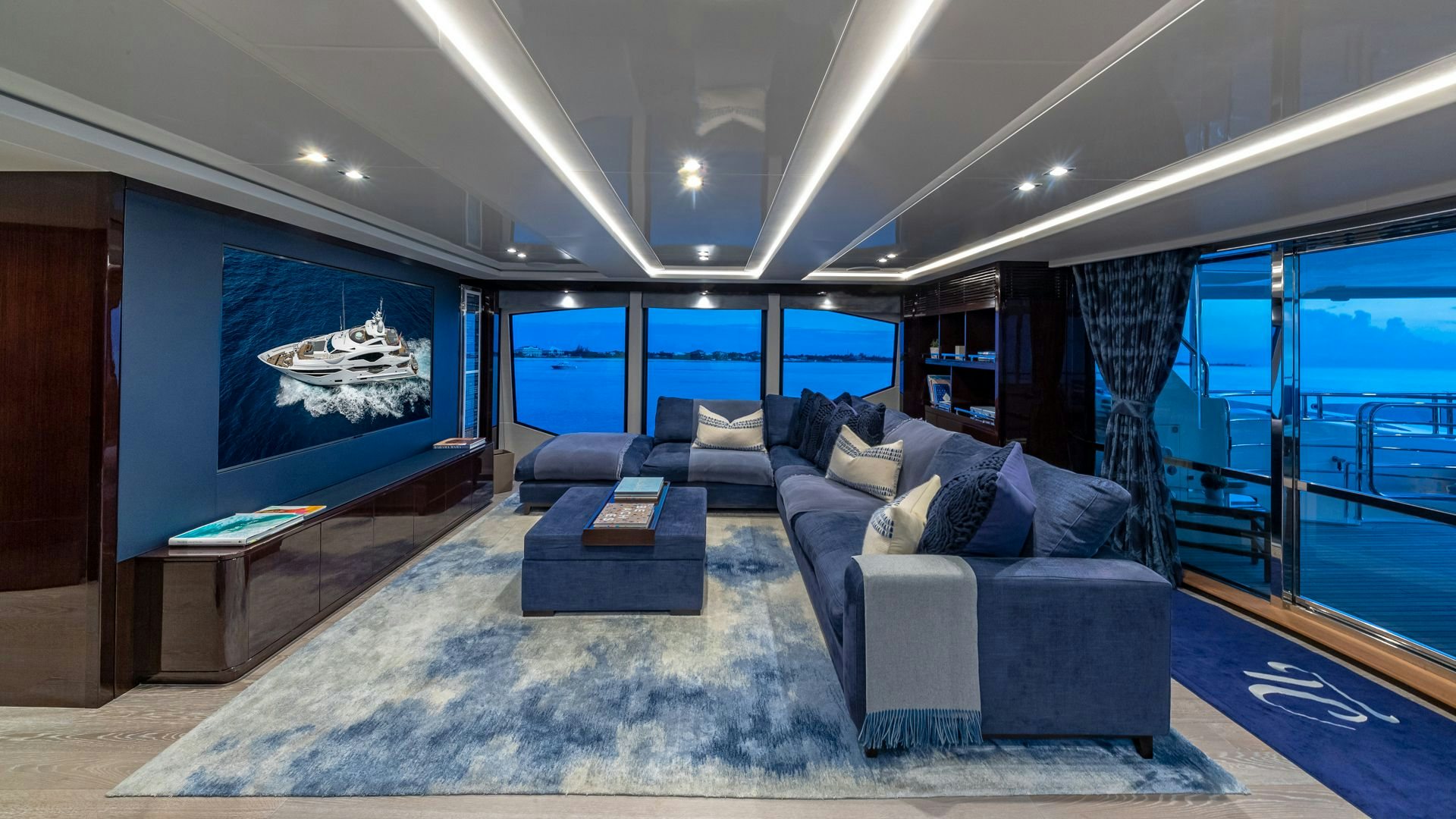 a large living room with a large blue couch and a large screen aboard CAPTAIN MORGAN III Yacht for Sale
