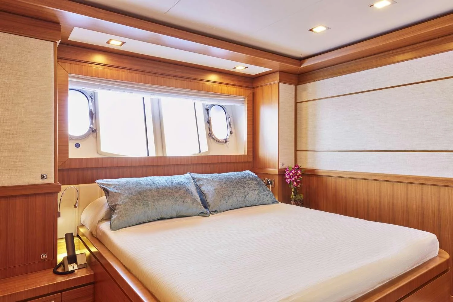 a bed with a white sheet and pillows in a room with a mirror aboard BEST OFF Yacht for Charter