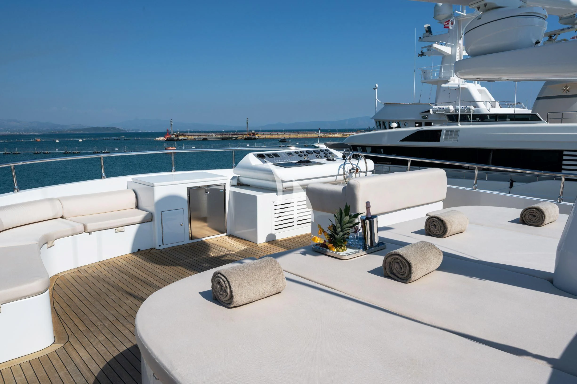a deck with a view of the ocean and a deck with a large yacht aboard TANANAI Yacht for Sale