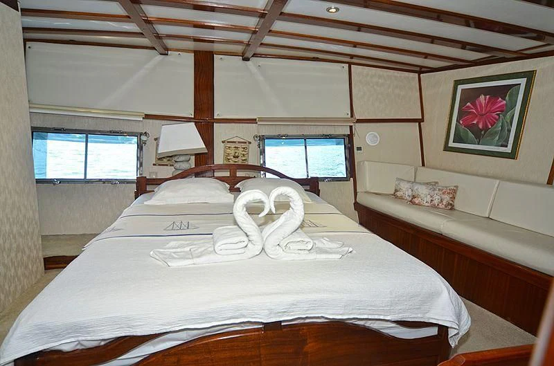 a bed with a white sheet and a white pillow on it aboard WHITE SWAN Yacht for Sale