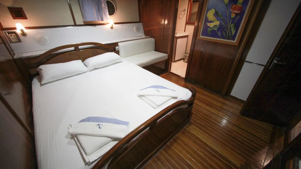 a bed with a white sheet and a white pillow on it aboard WHITE SWAN Yacht for Sale