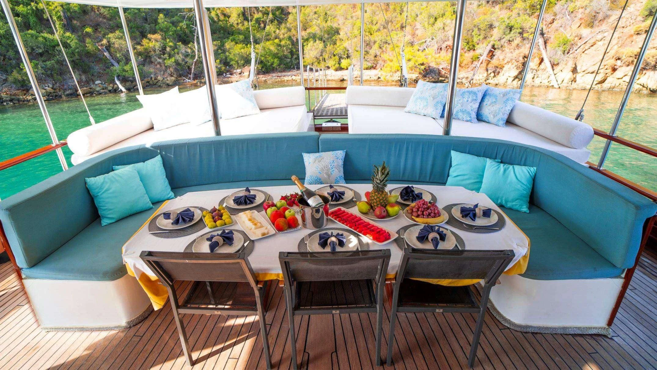 a blue couch with a table and chairs on it aboard WHITE SWAN Yacht for Sale