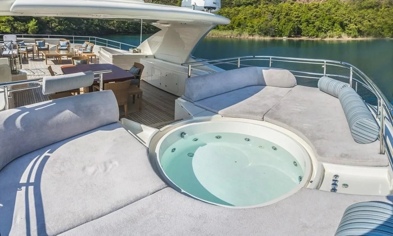 a pool with a lounge chair and a table and chairs on the side aboard ARIELA Yacht for Sale