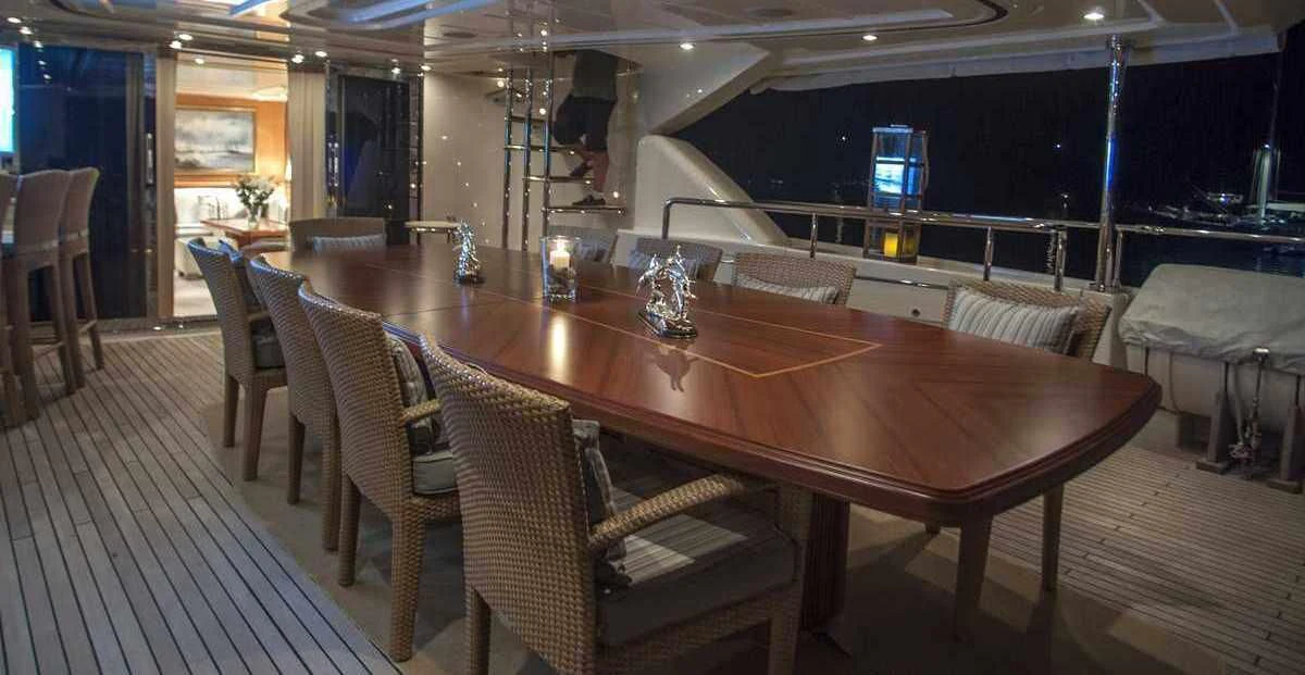 a large wooden table with chairs around it aboard ARIELA Yacht for Sale