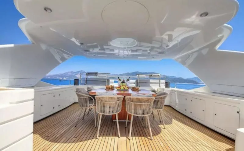 a large white boat with a table and chairs on a deck aboard ARIELA Yacht for Sale