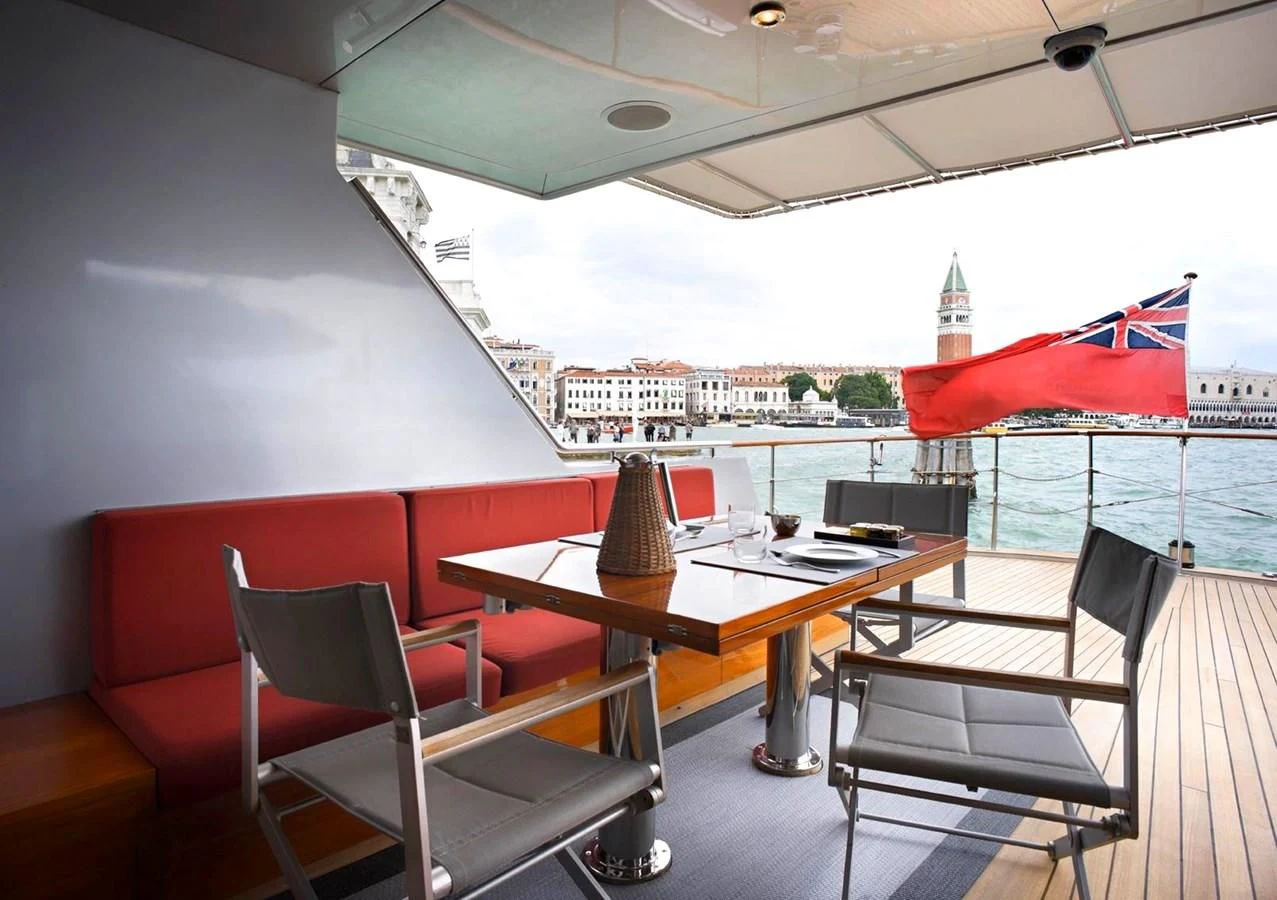 a table with chairs and a red umbrella on it aboard TEMPEST WS Yacht for Charter
