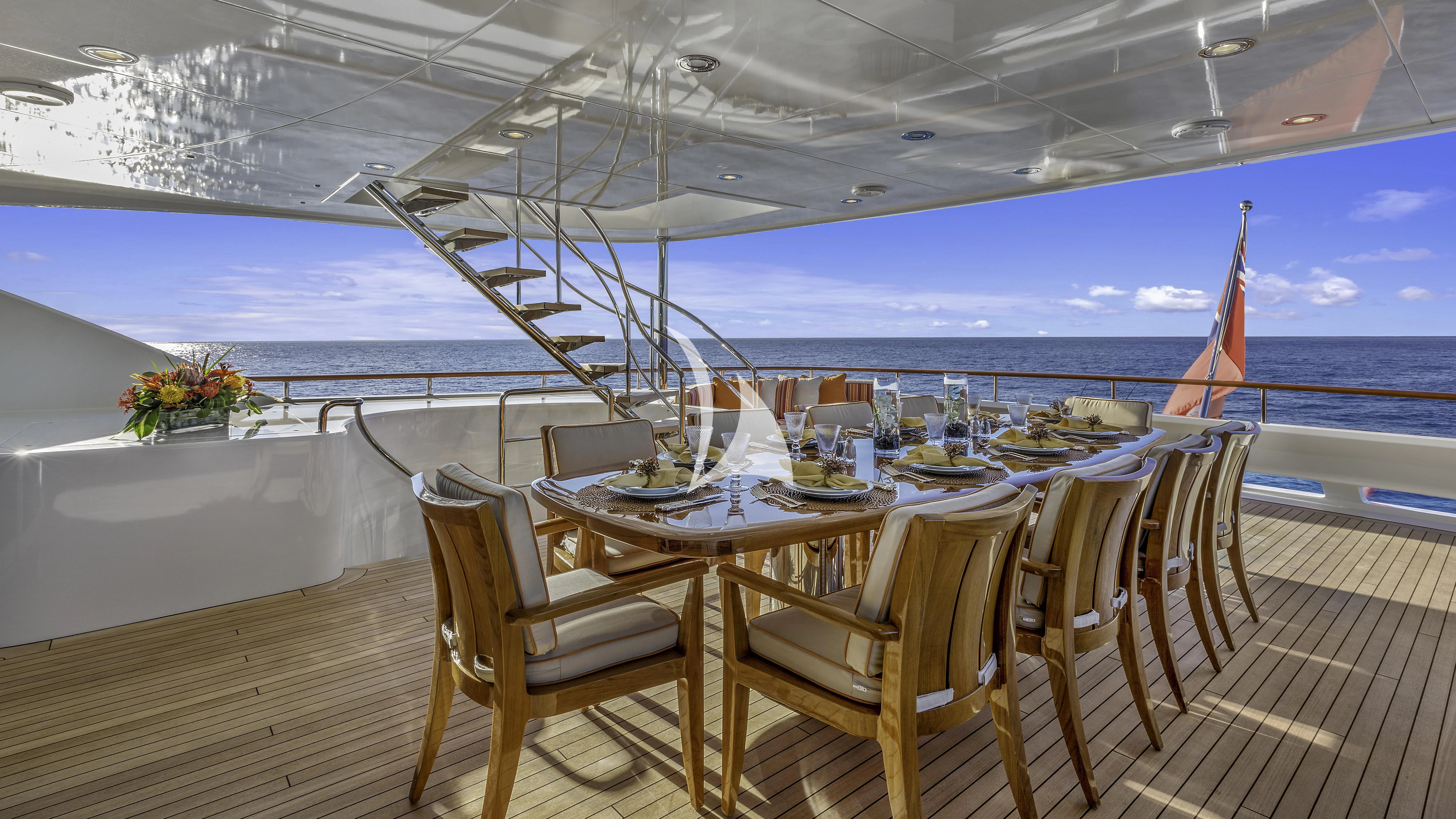 a table set for a dinner on a deck overlooking the ocean aboard AVALON Yacht for Sale