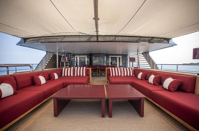 a red couch and a table on a boat aboard MASQUENADA Yacht for Sale