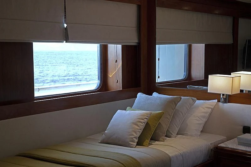 a bed with pillows and a window aboard MASQUENADA Yacht for Sale