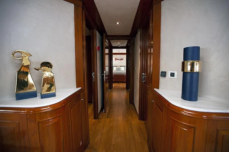 a hallway with a wood floor and a blue lamp on the wall aboard MASQUENADA Yacht for Sale