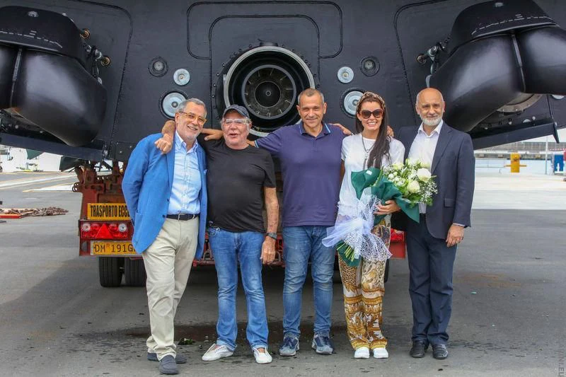 a group of people posing for a photo in front of a black train aboard FREEDOM Yacht for Sale
