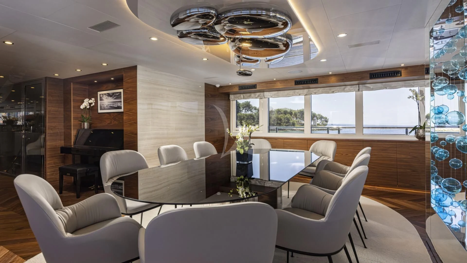 a room with a piano and a chandelier aboard M/Y ANTHEA Yacht for Sale