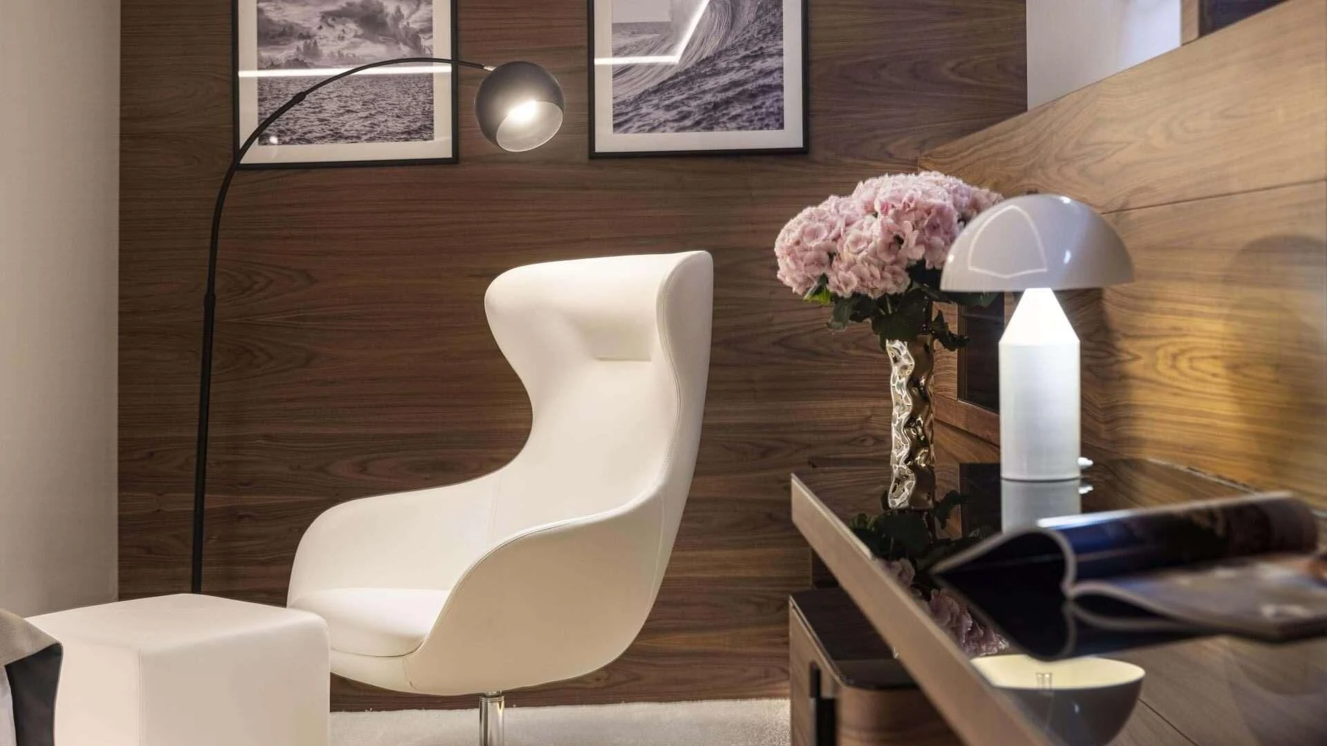 a white chair next to a white lamp and a vase with pink flowers aboard M/Y ANTHEA Yacht for Sale