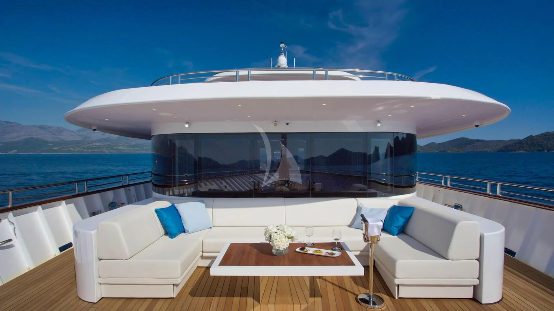 a large white boat with a white lounge chair and a table on a boat in the water aboard M/Y ANTHEA Yacht for Sale