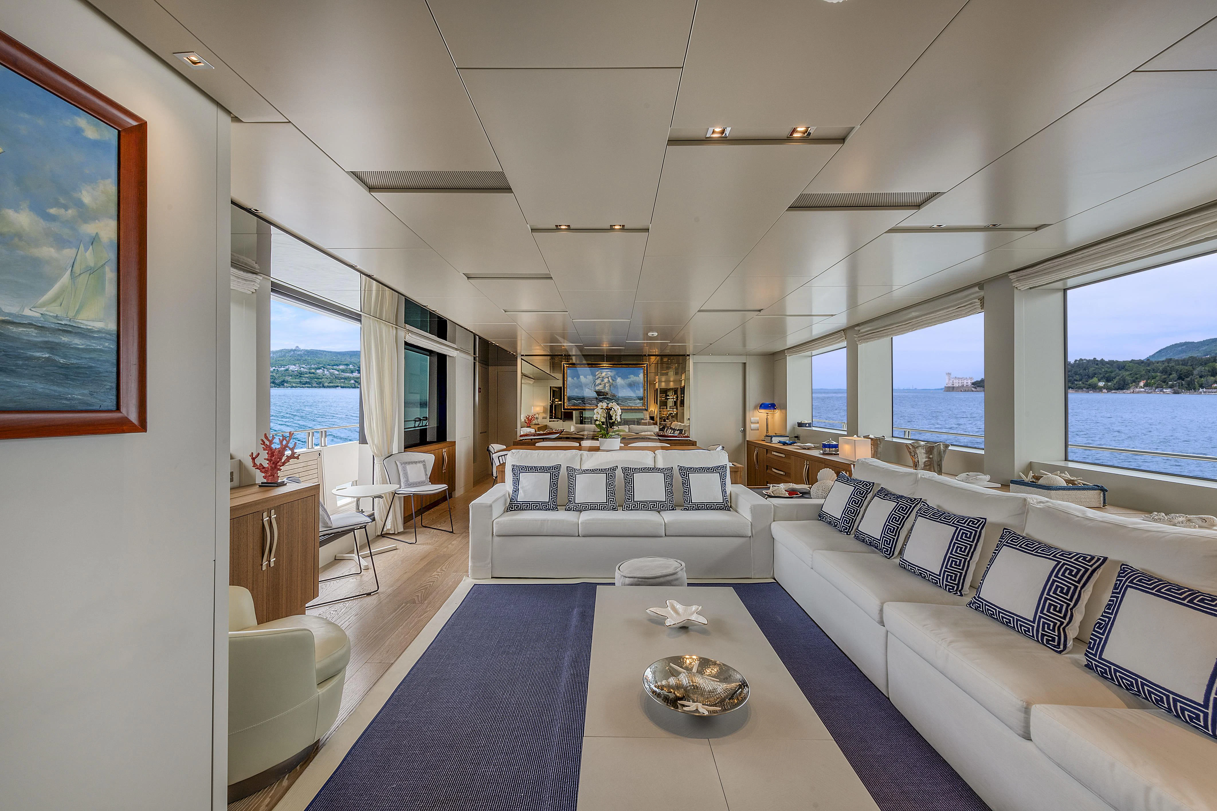 a living room with a large blue rug and white couches aboard VITTORIA Yacht for Charter