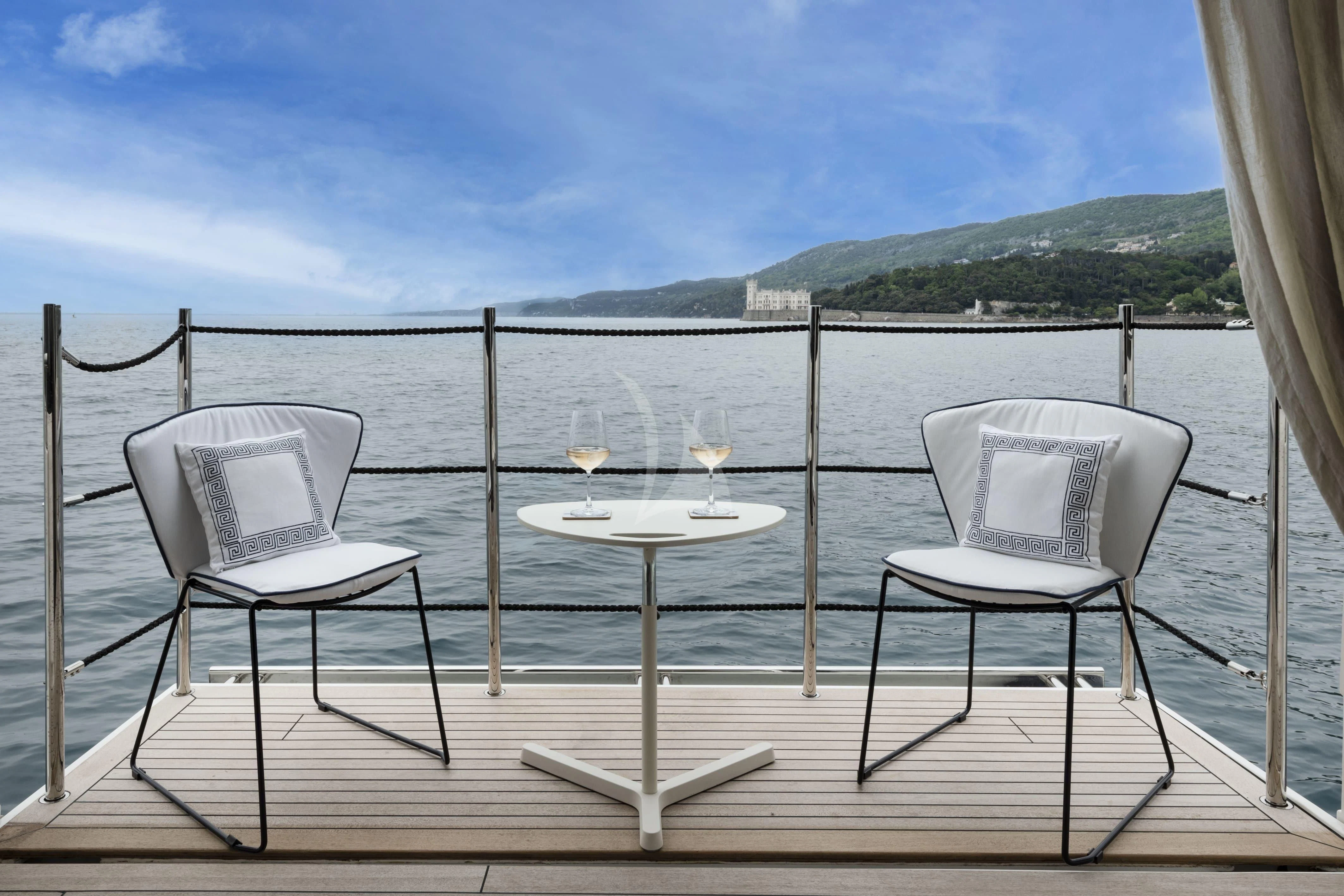 a table and chairs on a deck overlooking a body of water aboard VITTORIA Yacht for Charter